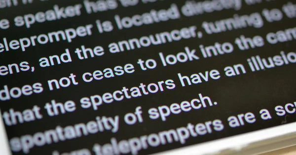 A close-up of a teleprompter. The text is white against a black background, and it discusses how a teleprompter works.