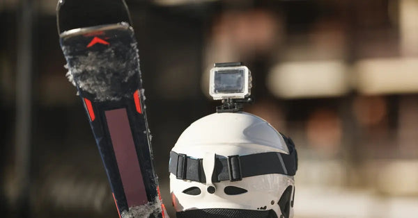 A person in full skiing gear faces away from the camera. There is a small video camera attached to their helmet.